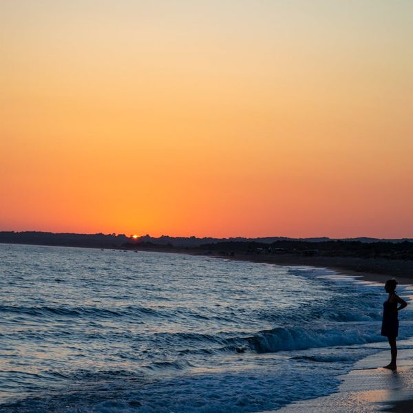 Silhouette of a person meditating against a vibrant sunrise.